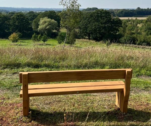 Bench overlooking a view of trees and fields into the distance