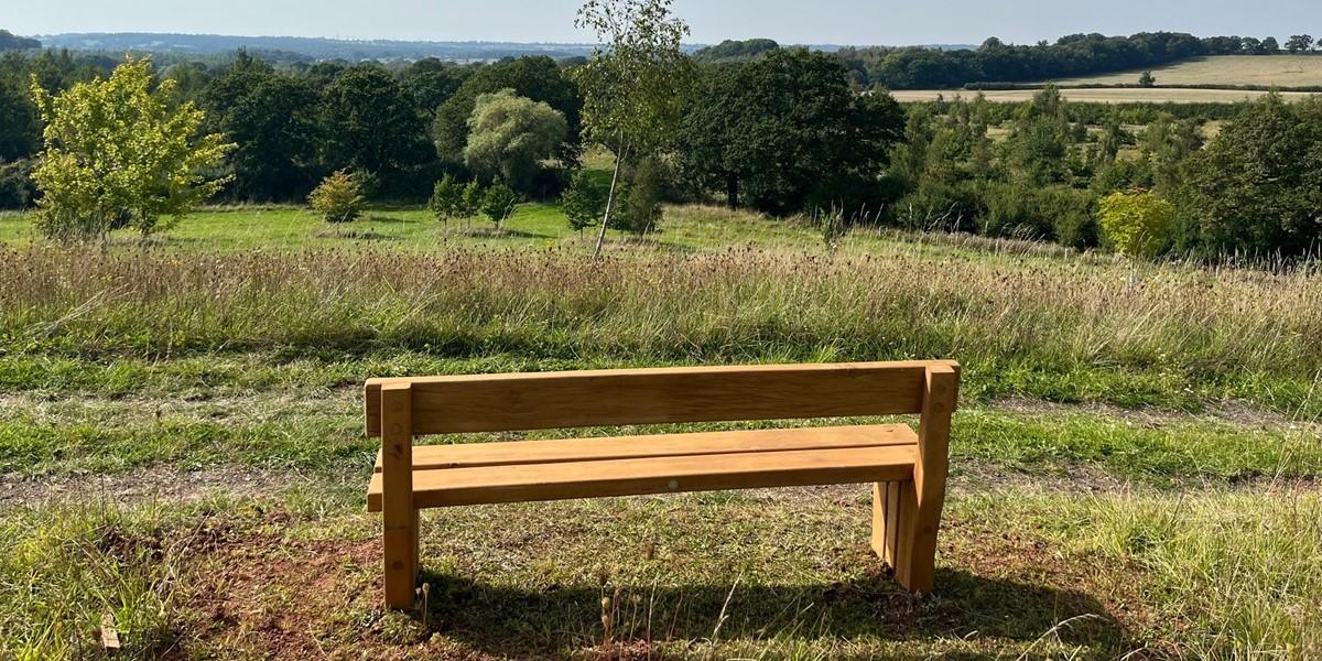 Bench overlooking a view of trees and fields into the distance