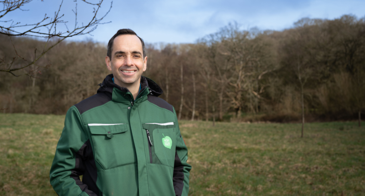 A head and shoulders photo of James with an open areas of Forest and mature trees in the background